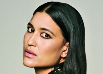 Close-up portrait of Julia Jones with sleek, side-parted black hair, softly smoky eye makeup and muted pink lipstick.